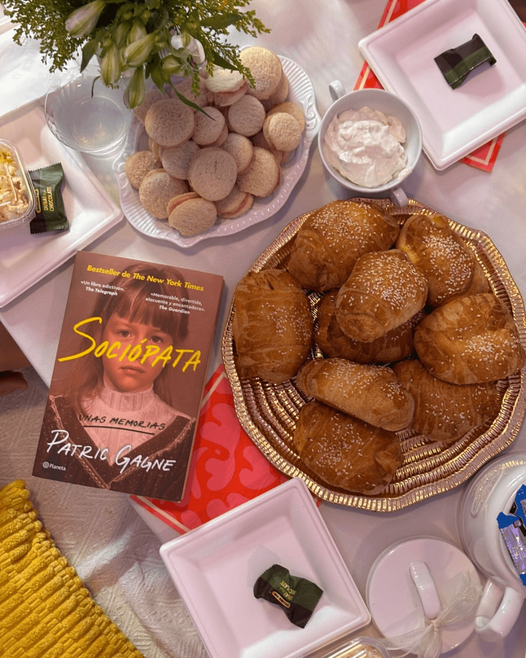 Mesa de picnic con pan dulce, sandwiches y el libro Sociópata